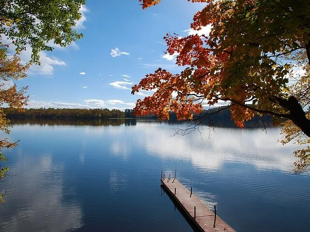 Ruhiger See mit Holzsteg und farbenprächtigem Herbstlaub